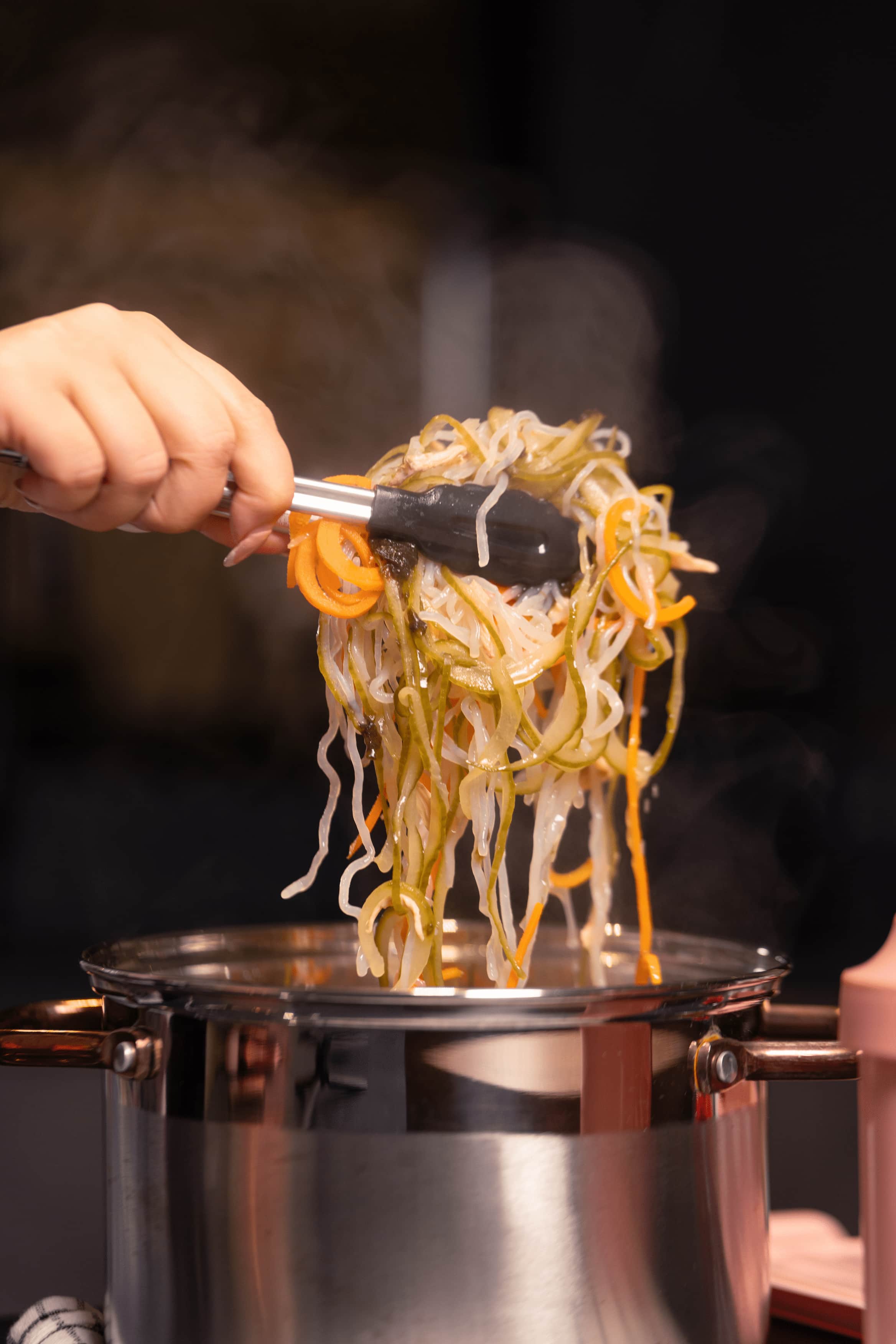 Steaming ramen noodles being lifted from a pot